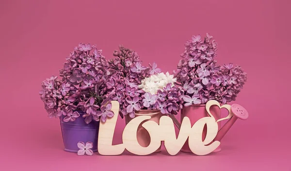Word Love and lilac flowers on pink background. St. Valentine Day, love or wedding day concept. Romantic pink background with word Love and  flowers, copy space