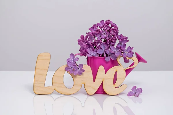 Word Love and lilac flowers on white background. St. Valentine Day, love or wedding day concept. Romantic white background with word Love and  flowers, copy space
