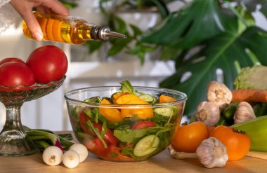 Sebze salatasının üzerine zeytin yağı dökülüyor. Kâsede organik yaz salatası. Domatesli, salatalıklı, biberli, soğanlı taze Yunan salatasına zeytinyağı dök. Sağlıklı yiyecekler, yakın plan.