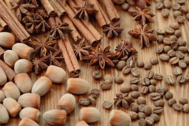 Background with cinnamon sticks, anise stars, coffee beans and nuts. Spicy trendy background. Close-up of various spices on wooden table top view