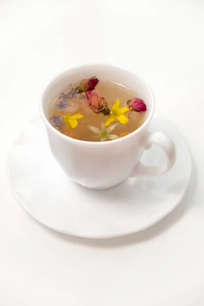 stock image A white cup with fragrant herbal tea and flowers is the perfect choice for health and wellness. Tea time. Relaxing with herbal tea, white background, top view, vertical