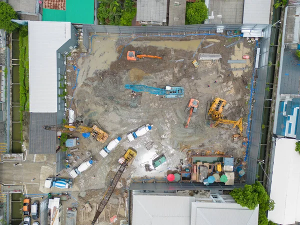 İnşaat işçileri altında vinç ve kazıcılarla çalışan yoğun endüstriyel hava manzarası. Çelik kaplı döşeme öncesi beton döşeme manzarası. Yüksek binalı mimari bina geliştirme.