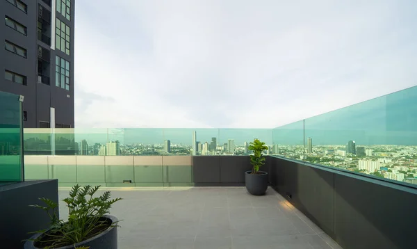 Sky garden on private rooftop of condominium or hotel, high rise architecture building with tree, grass field, and sunset sky.