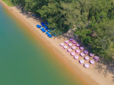 Aerial top view of umbrellas on beach, shore and clear blue turquoise seawater, Andaman sea in summer season. Water in ocean material surface pattern texture wallpaper background.