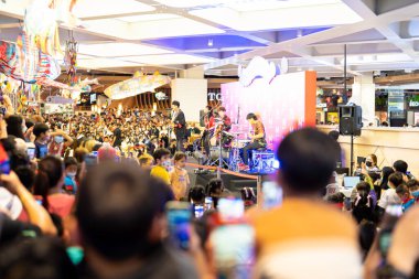 Crowd, group of young people kid, cheering in live music concert in front of colorful stage lights in school. Children event