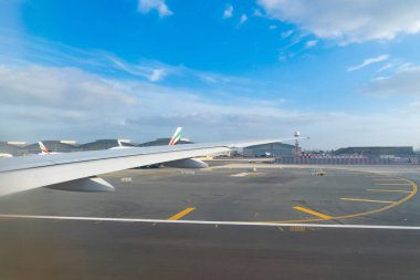 Bir uçak jetinin uçuş ve iniş kanadı, havaalanındaki pist penceresinden kentsel şehir manzaralı binalar. Seyahat ve ulaşım kavramı.