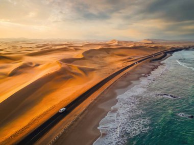 Namib Desert Safari ile cadde yolunun havadan görünüşü, kum tepesi, Namibya, Güney Afrika 'da sahil denizi. Gün batımında doğal manzara. Ünlü turist eğlencesi. Büyük Kanyon 'da kum