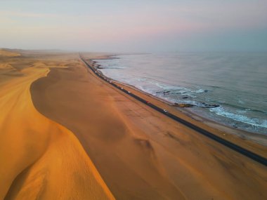 Namib Desert Safari ile cadde yolunun havadan görünüşü, kum tepesi, Namibya, Güney Afrika 'da sahil denizi. Gün batımında doğal manzara. Ünlü turist eğlencesi. Büyük Kanyon 'da kum