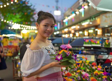 Tayland 'da Loy Krathong' la birlikte Asyalı Taylandlı bir kadının portresi. Yerel pazar festivalinde suyun üzerinde yüzüyor. Kutlama ve Kültür. İnsanlar geceleri tatil yapar. Tayland etkinliği. İnsan yaşam tarzı.
