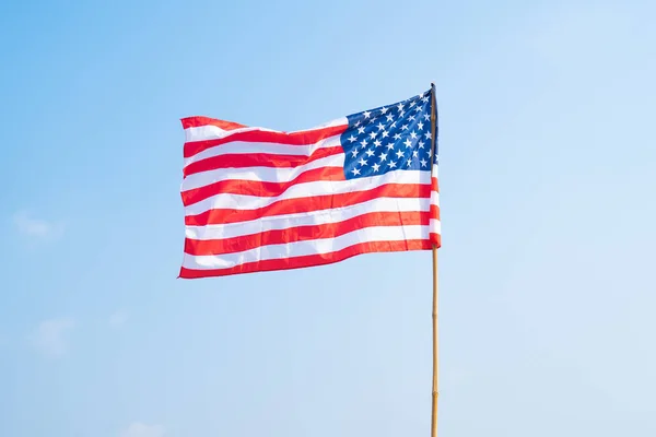 United States of America national flag blowing in the wind isolated for 4th of July or Independence Day. Official patriotic design. Waving sign with blue sky.