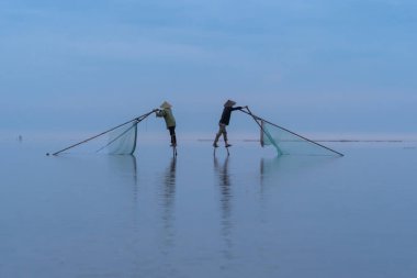 Vietnamlı balıkçıların silueti, Vietnam 'daki Asya' da sabah saatlerinde doğa gölünde ya da nehirde taze su balığı yakalamak için ağ tutuyor. İnsanlar.