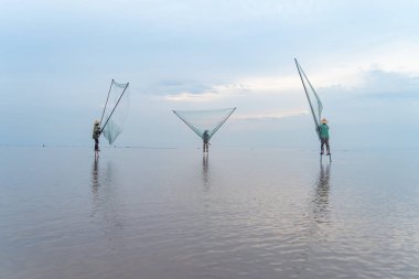 Vietnamlı balıkçıların silueti, Vietnam 'daki Asya' da sabah saatlerinde doğa gölünde ya da nehirde taze su balığı yakalamak için ağ tutuyor. İnsanlar.