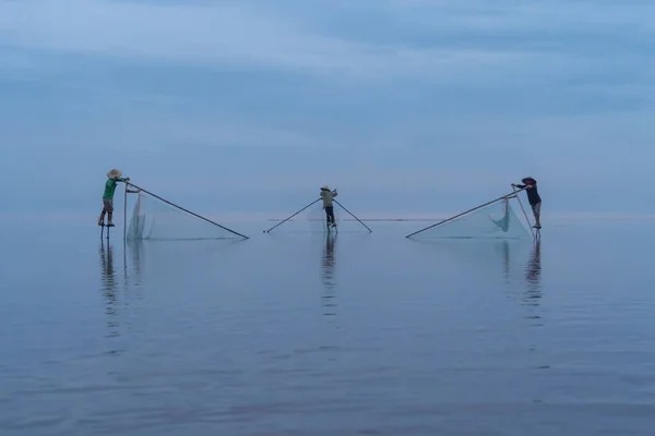 stock image Silhouette of Vietnamese fisherman holding a net for catching freshwater fish in nature lake or river with reflection in morning time in Asia in Vietnam. People.