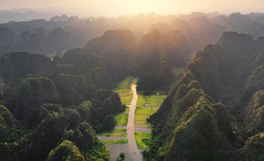 Taze çeltik pirinç ve göl nehrinin havadan görünüşü, Asya ve Vietnam 'daki Ninh Binh kırsalında dağ tepeleri vadisi olan yeşil tarım alanları. Doğa manzarası arka planı.