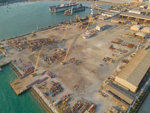 Aerial view of busy industrial under construction site workers working with cranes and excavators. Top view of precast concrete slap floor full of steel. Container port.
