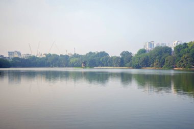 Modern gökdelen binaları olan kaplumbağa kulesi ve Hanoi şehir merkezindeki ağaçlarla birlikte halk parkındaki Hoan Kiem Gölü 'nün ortasındaki yansıma. Gün batımında şehir, Vietnam. Şehir manzarası arkaplanı.