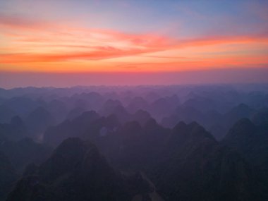 Orman ağaçlarının ve sisli, bulutlu yeşil dağ tepelerinin havadan görünüşü. Doğa manzarası arka planı, Vietnam.