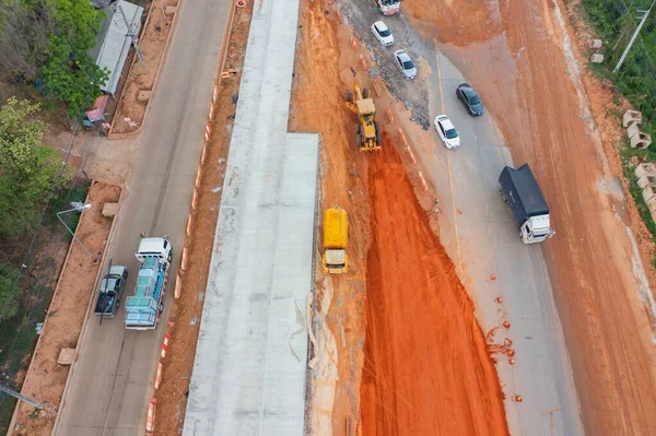 Aerial view of construction tractor car, bulldozer, or backhoe digging road or street in traffic transportation and agriculture concept. Engine working in urban city town.