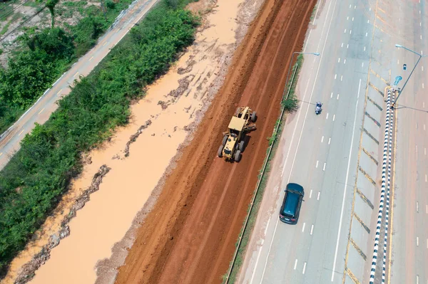 Aerial view of construction tractor car, bulldozer, or backhoe digging road or street in traffic transportation and agriculture concept. Engine working in urban city town.