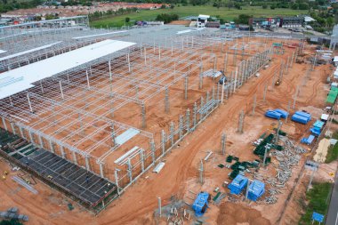 İnşaat işçileri altında vinç ve kazıcılarla çalışan yoğun endüstriyel hava manzarası. Çelik kaplı döşeme öncesi beton döşeme manzarası. Geliştirme mimari binası.