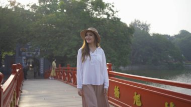 Asyalı Vietnamlı bir kadının portresi Hanoi şehir merkezindeki Hoan Kiem Gölü 'ndeki ağaçlarla halka açık park bahçesindeki Kızıl Köprü' de seyahat ediyor. Şehir, Vietnam...