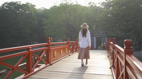 Asyalı Vietnamlı bir kadının portresi Hanoi şehir merkezindeki Hoan Kiem Gölü 'ndeki ağaçlarla halka açık park bahçesindeki Kızıl Köprü' de seyahat ediyor. Şehir, Vietnam...