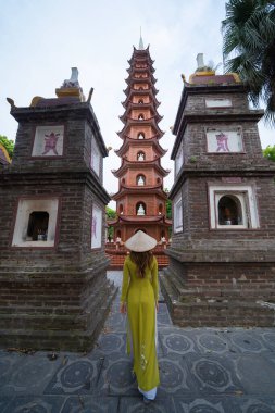 Tran Quoc tapınağında Vietnam elbisesi ve hasır şapkalı Asyalı Vietnamlı bir kadının portresi. Vietnam 'ın Hanoi kentindeki turistik bölge. İnsan yaşam tarzı.