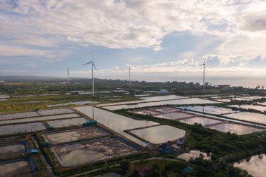 Rüzgar türbinlerinin ya da yel değirmenlerinin hava manzarası ve sanayi fabrikasındaki deniz kıyısı sahili. Su gücü, sürdürülebilir yeşil temiz enerji ve çevre kavramı. Doğa yeniliği.