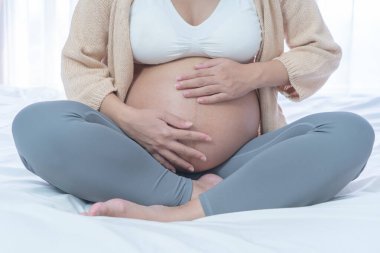 Evdeki yatak odasında mutlu hamile bir kadının portresini kapat. Bebek sahibi olmak. Aile hayatı işte. Annen seni seviyor.