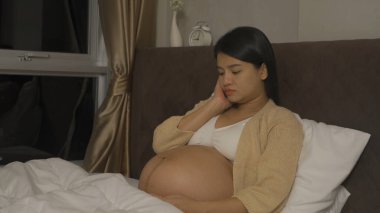 Evdeki yatak odasında depresyondaki Asyalı hamile kadın. Bebek sahibi olmak. Aile hayatı işte. Anne!.