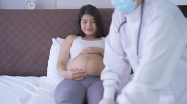 Mutlu Asyalı hamile kadın portresi. Yatak odasında bir doktorla birlikte. Bebek sahibi olmak. Aile hayatı işte. Annen seni seviyor.