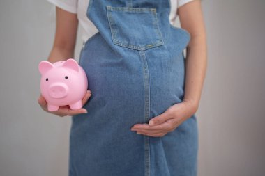 Mutlu Asyalı hamile bir kadının portresi, yatak odasında domuz kumbarası olan bebek için para biriktiriyor. Bebek sahibi olmak. Aile hayatı işte. Annen seni seviyor.