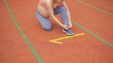 Plastik zeminde koşan mutlu Asyalı hamile bir kadının portresi, bir spor stadyumunda pist. Spor ve rekreasyon geçmişi. Bebek sahibi olmak. Aile hayatı işte. Anne yaşam tarzı..