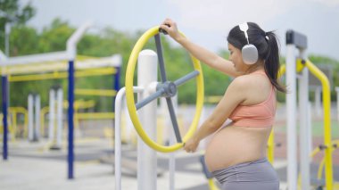 Jimnastik salonunda mutlu Asyalı hamile bir kadının portresi. Bebek sahibi olmak. Antrenman egzersizi. Spor malzemeleriyle içeride egzersiz yap. Atletik. Aile hayatı işte. Anne sevgisi. Rekreasyon.