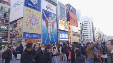 Bir grup insan, Japonya 'nın Osaka İlçesi' nde, şehir merkezindeki cadde üzerinde, zebra kavşağında ya da alışveriş merkezinde yaya geçidinde yürüyor..