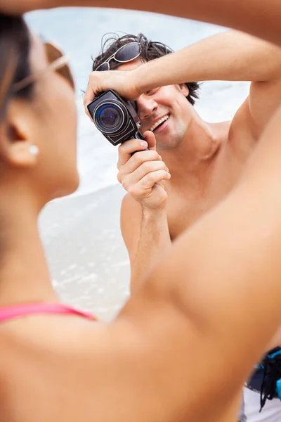 男と女のカップル ボーイフレンド取るビデオや撮影彼のガールフレンドでAビキニでザビーチで使用してレトロヴィンテージ映画カメラ — ストック写真
