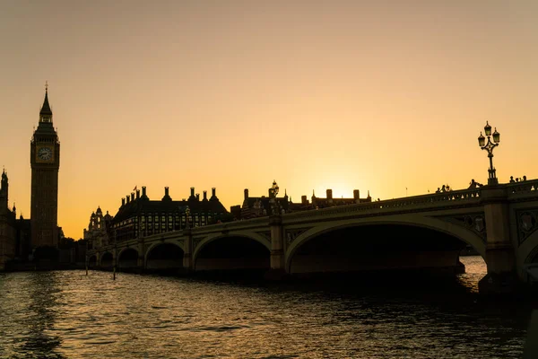 伦敦日落时分 一些无名游客穿过威斯敏斯特桥 走向议会大厦和大本钟 — 图库照片