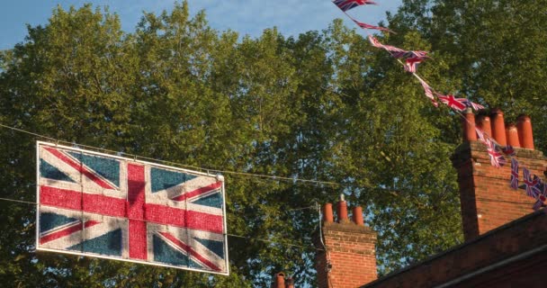 イギリスの路上で家や煙突から飛んでくるユニオンジャックの旗 スローモーション4Kビデオクリップ — ストック動画