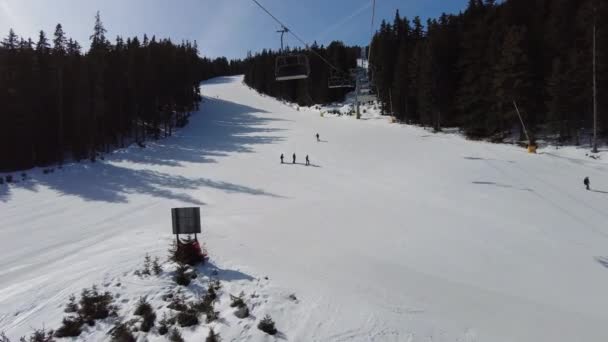 视频剪辑四人滑雪椅电梯穿过树木上山的蓝天 — 图库视频影像