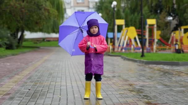傘屋外で幸せな少年は 雨の中で傘を持つ子歩く — ストック動画