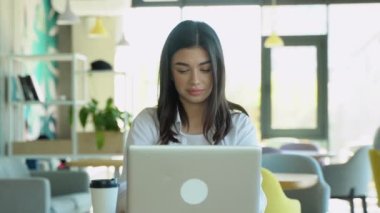 Gülümseyen kız müşteriyle kafede dinlenirken sohbet ediyor, dizüstü bilgisayar kullanıyor..