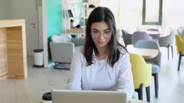 Gülümseyen kız müşteriyle kafede dinlenirken sohbet ediyor, dizüstü bilgisayar kullanıyor..