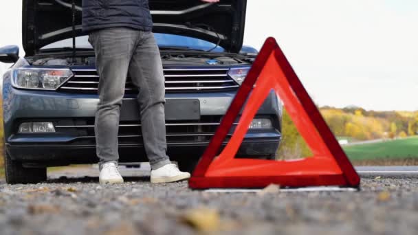 路边警告三角形 警告即将到来的车辆抛锚 与一个男子使用他的手机呼救 旅行概念 — 图库视频影像