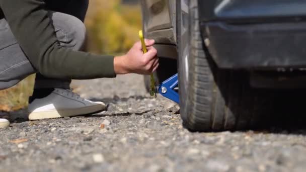 道路で故障した灰色の車を持つ若い男 道路上の壊れた車のタイヤを変更します 旅行の概念 — ストック動画