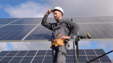 Gururlu genç bir mühendisin portresi kollarını kavuşturarak yaptığı işten memnun bir şekilde gülümsüyor. Kavram: yenilenebilir enerji, teknoloji, elektrik, hizmet, yeşil güç