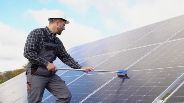 男性工程师用刷子和水清洁太阳能电池板 — 图库视频影像
