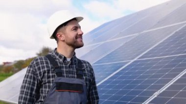Üniformalı erkek mühendis muayene için güneş paneli alanında yürüyor. Ekolojik yapı. Güneş enerjisi santrali. Yeşil enerji kavramı.