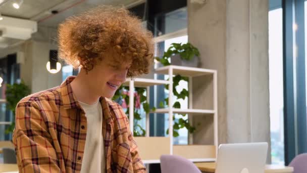 Молодий Рудий Кучерявий Чоловік Сидить Столом Кафе Працює Ноутбуці Носить — стокове відео
