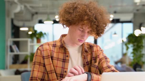 Young Red Haired Curly Man Sitting Cafe Uses Smart Watch — Stock Video