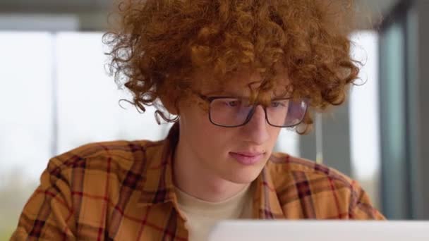 Skupiony Rudy Mężczyzna Okularach Pomocą Laptopa Siedzi Biurze Poważny Nastolatek — Wideo stockowe